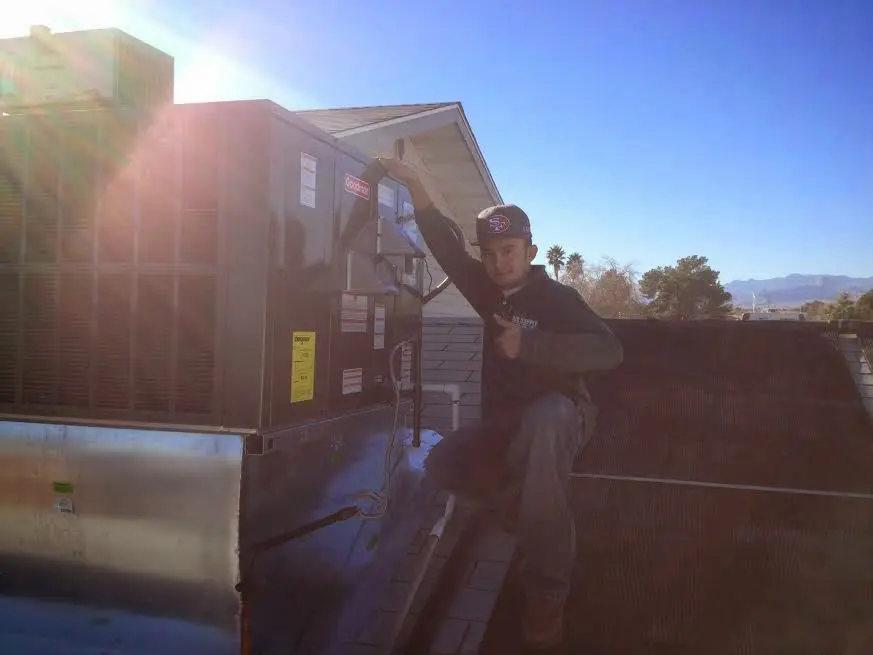 HVAC technician performing AC Tune-Up on a rooftop unit in Clifton